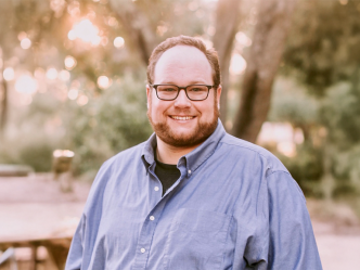 male wearing glasses smiling outside