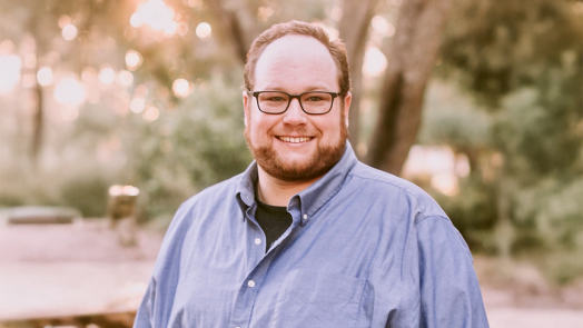 male wearing glasses smiling outside