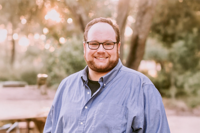 male wearing glasses smiling outside