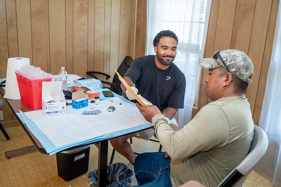 A healthcare worker hands information to a patient during a rural health clinic.
