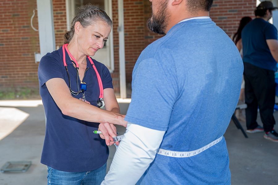 A healthcare worker takes measurements of a patient's waist during a clinic.