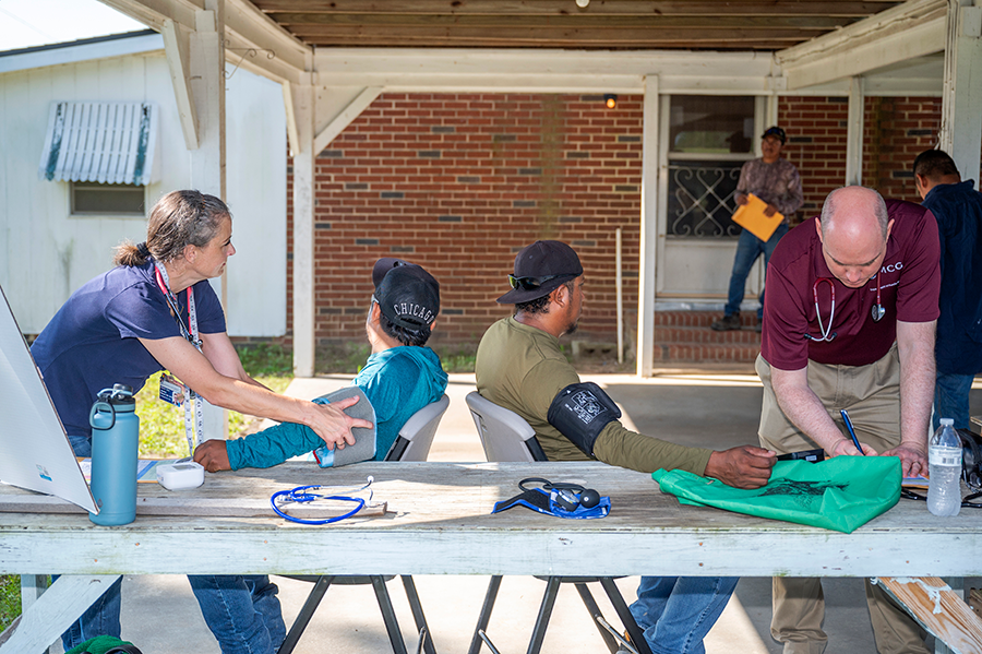 Two healthcare workers check the blood pressure of two patients during a rural health clinic.