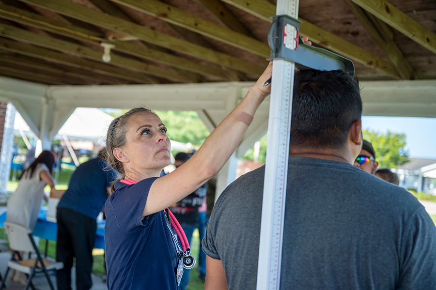 A healthcare worker measures a patient's height.