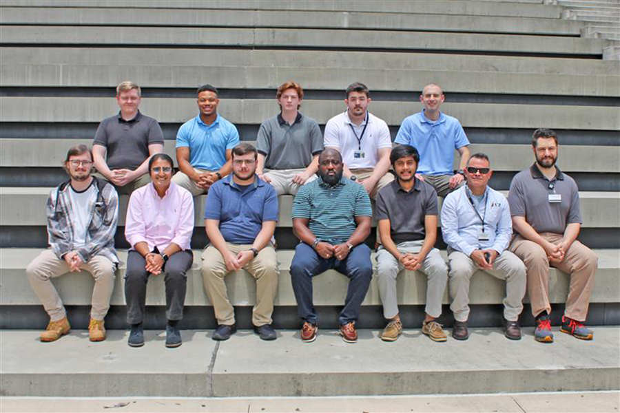 A group of college interns and staff sit on a series of concrete steps.
