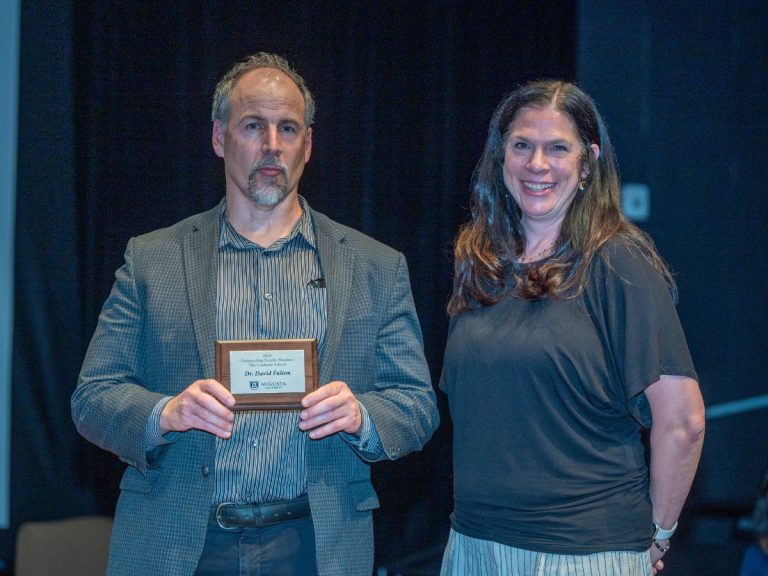 A man holding a small plaque stands next to a woman smiling at the camera.