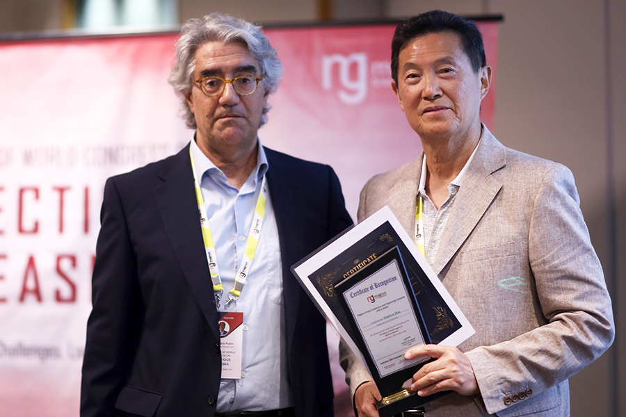 Two men standing on a stage. One man just finished presenting at a scientific symposium.