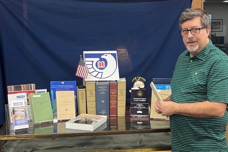 Man stands next to set of books about government