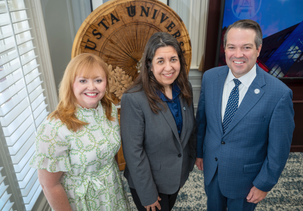 Two women and a man smile for a photo.