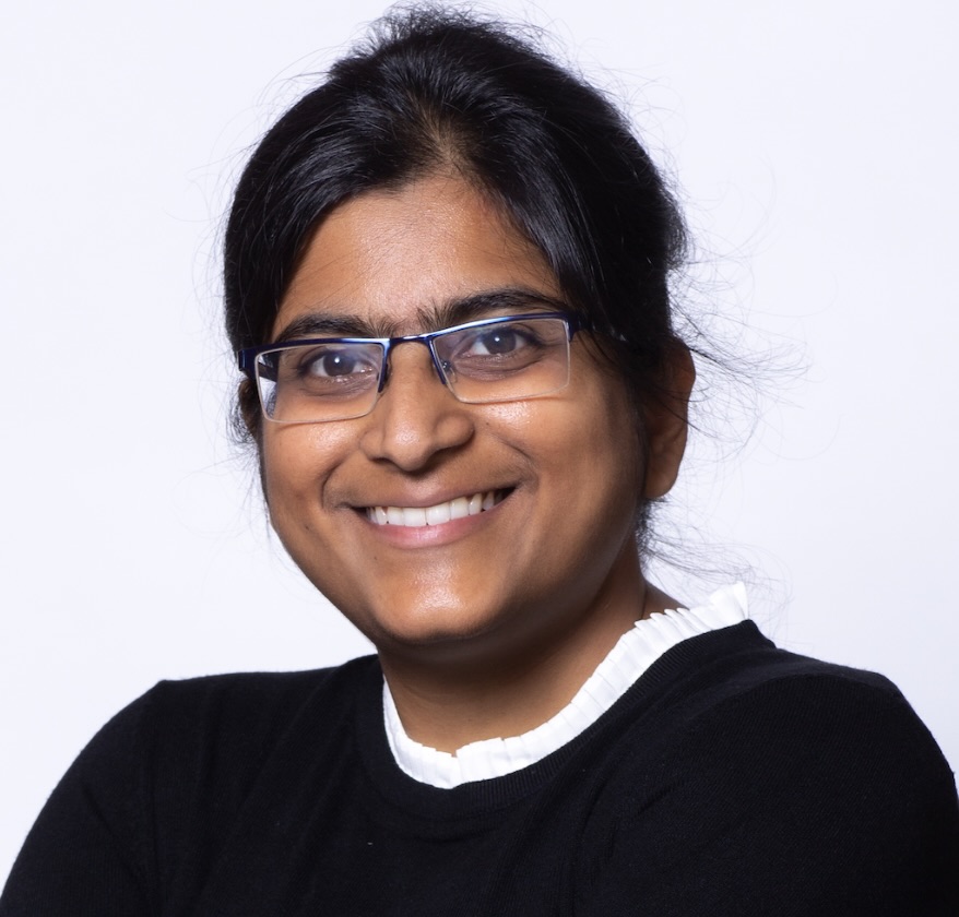 A woman in a black and white shirt smiles.