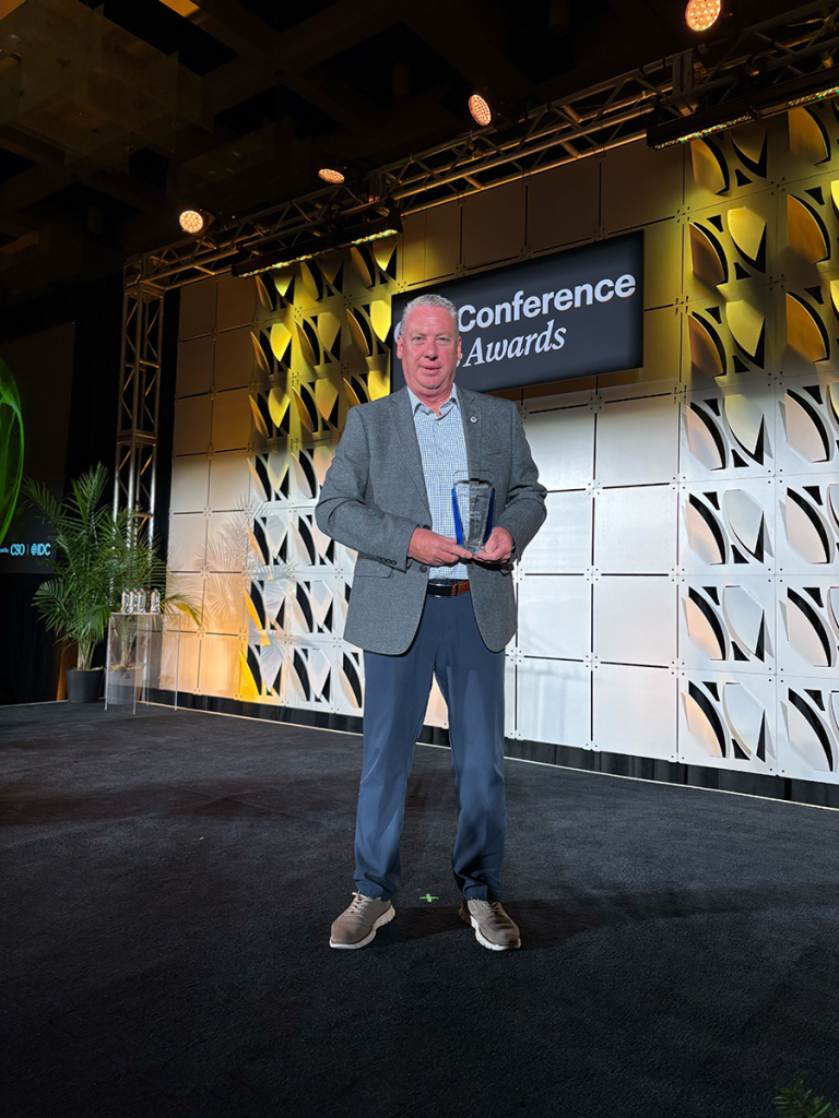 A man stands on a stage holding an award.