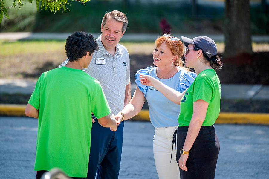 A man and a woman meet with volunteers during a move-in event for a university.