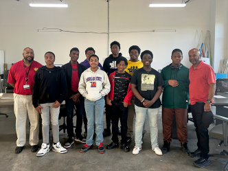 A group of middle and high school students with two counselors stand in a large room.