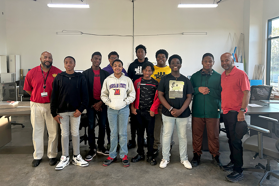 A group of middle and high school students with two counselors stand in a large room.