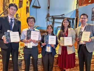 A group of five researchers stand smiling while holding their awards