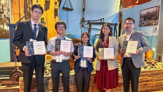 A group of five researchers stand smiling while holding their awards