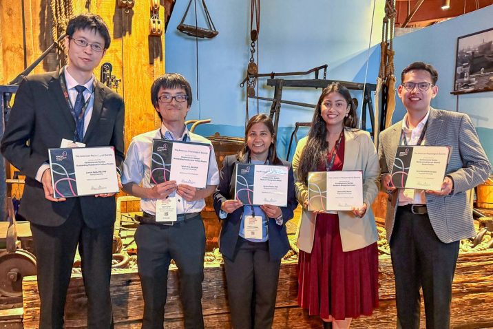 A group of five researchers stand smiling while holding their awards