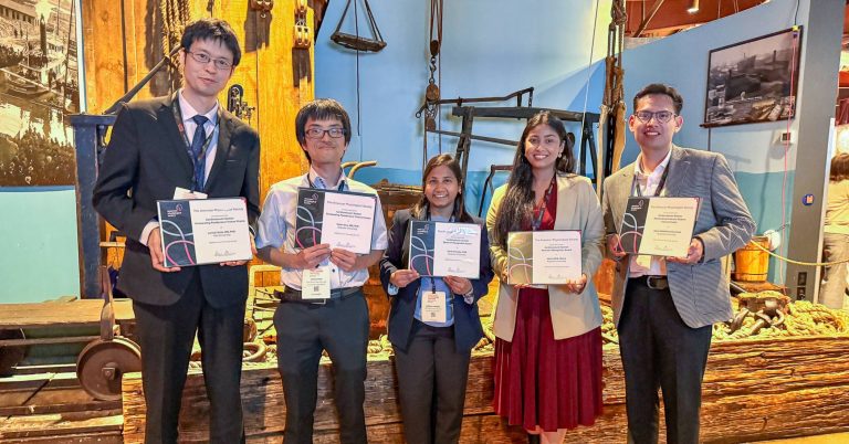 A group of five researchers stand smiling while holding their awards