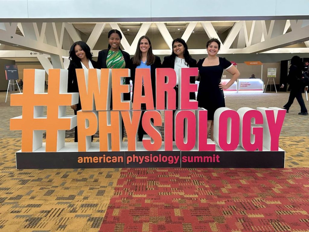 five students standing next to display reading "#WEAREPHYSIOLOGY