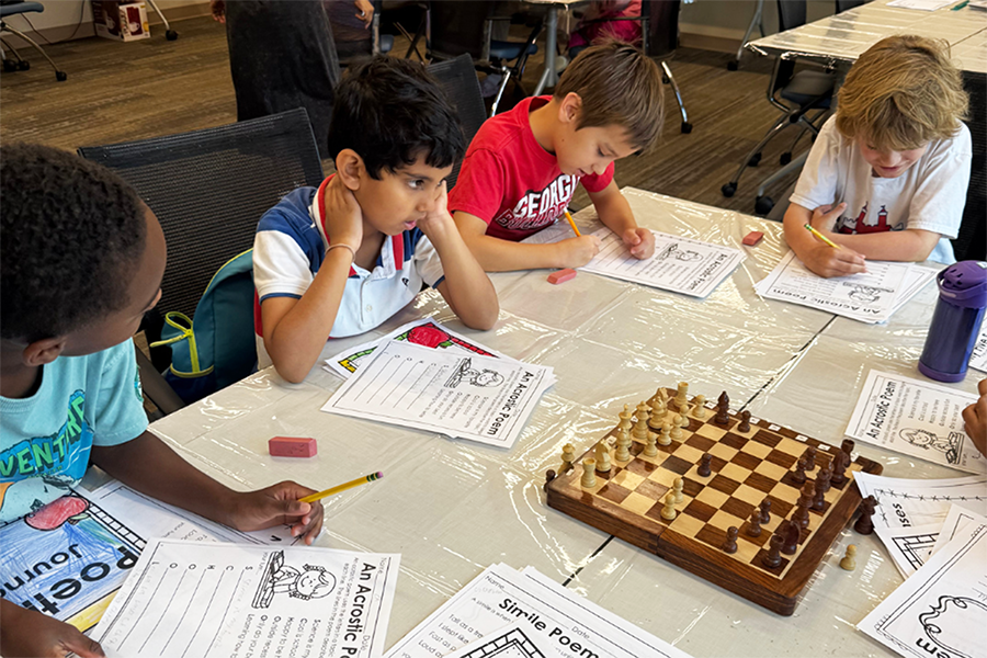 Elementary-aged kids work on a puzzle activity that includes a chess board.