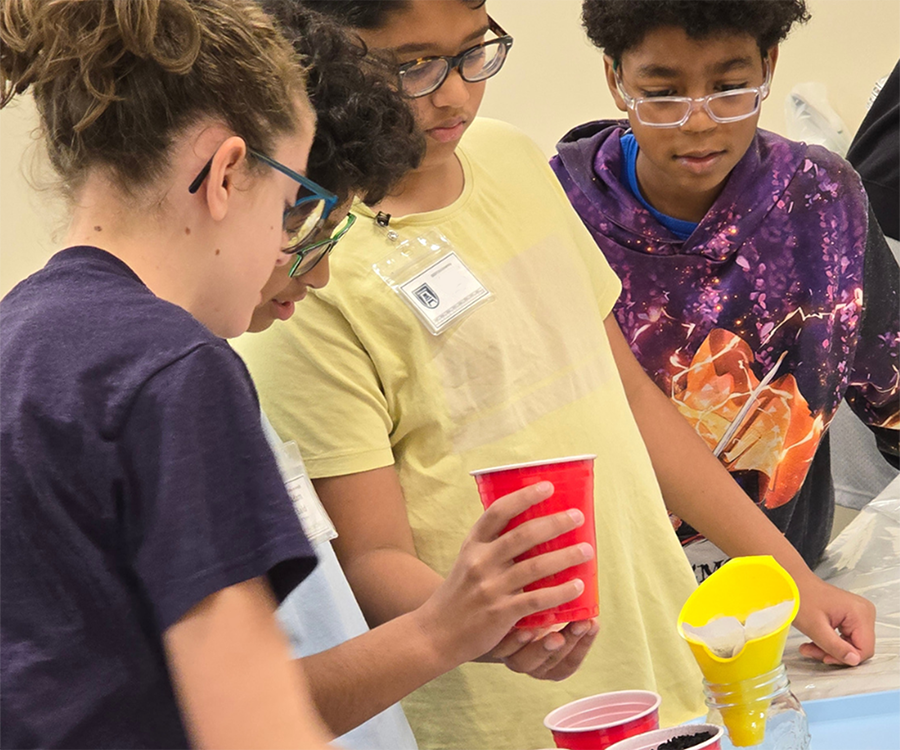 Four elementary-aged children work on a small science experiment during a summer camp.