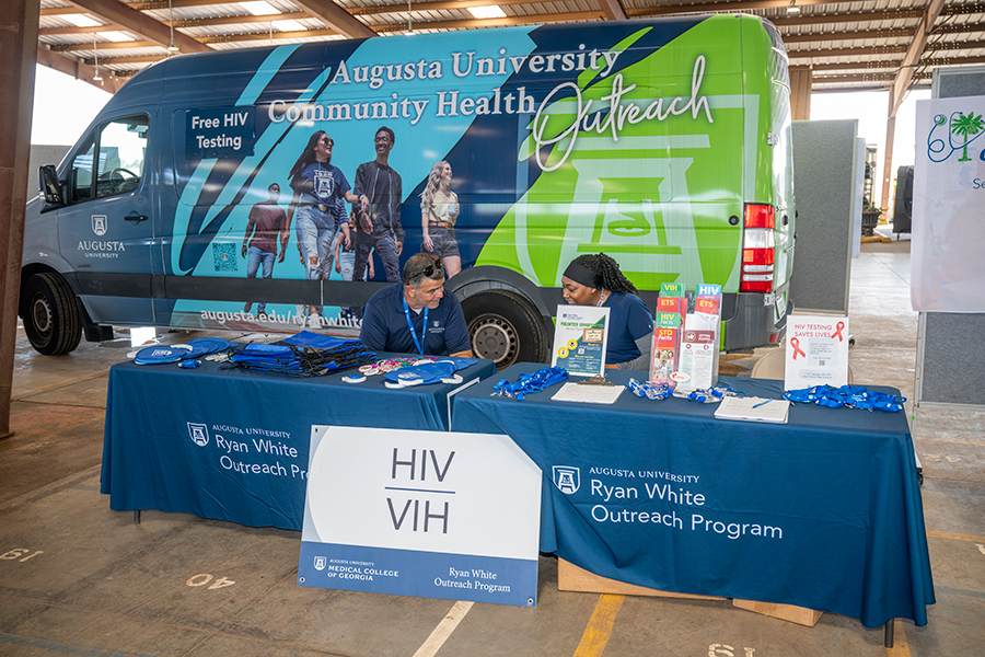 A man and a woman sit at an information table during a rural health fair inside a loading dock.