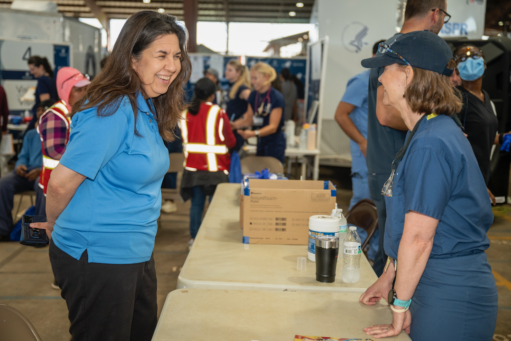 Two women laugh while talking during a rural health fair.