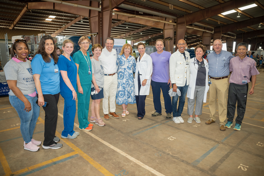 A large group of people stand in the middle of an open-air loading dock. There are 13 people.