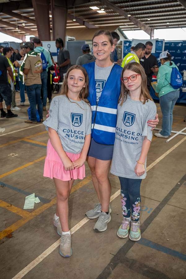 Woman stands with her arms around two young girls.