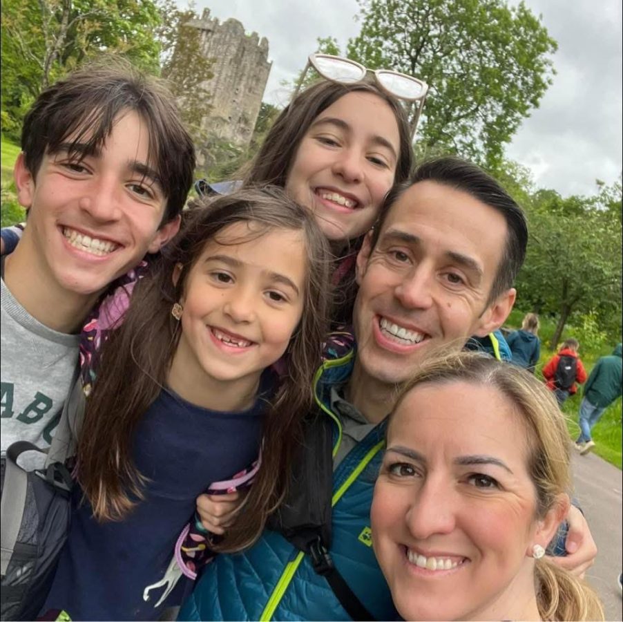 A man and woman with three children smiling in front of a castle.