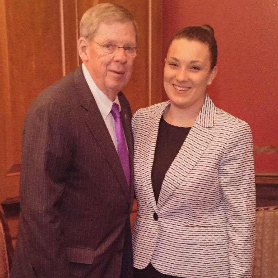 Man in a suit poses with a smiling woman in a suit.