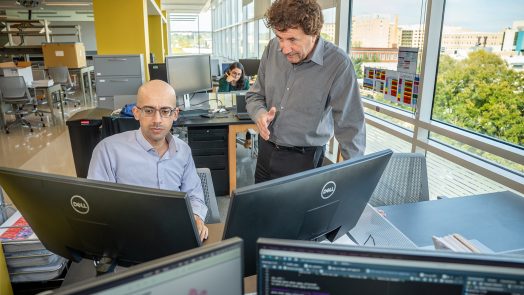 Two men at computers in a modern science lab.