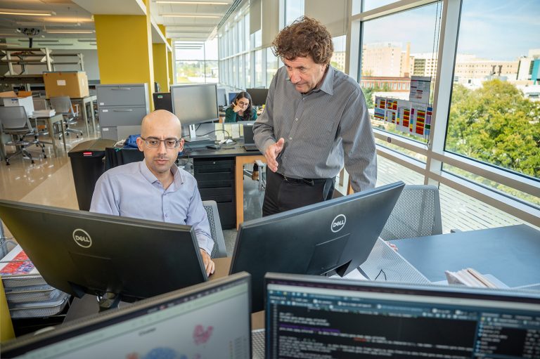 Two men at computers in a modern science lab.