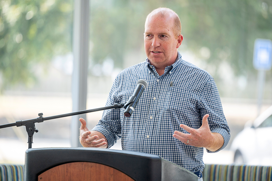 A man stands at a podium and speaks to a large group of people gathered for a ceremony.