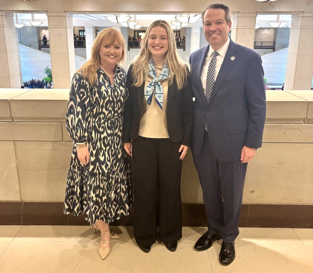 Two women and a man in business attire stand in the U.S. Capitol Building