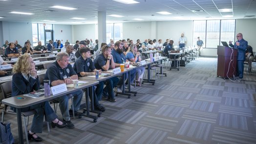 Man talking at a podium in front of men and women