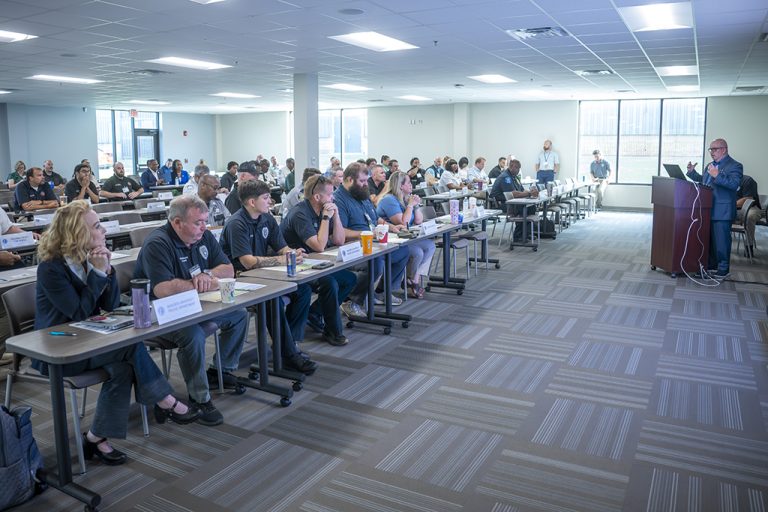 Man talking at a podium in front of men and women
