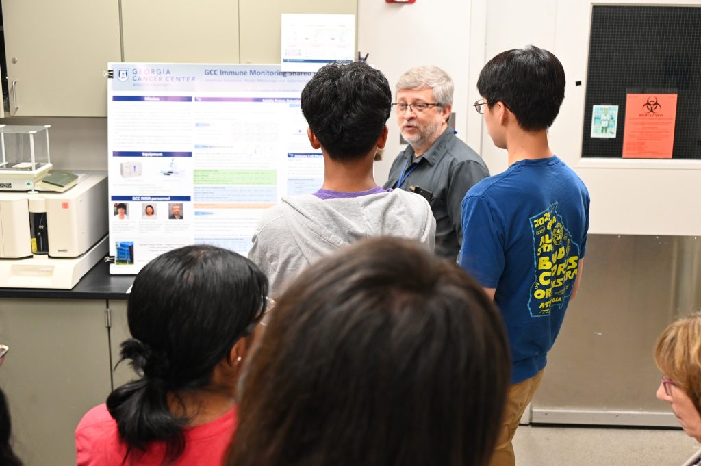 A scientist talks to a group of high school and college students about the research he conducts.
