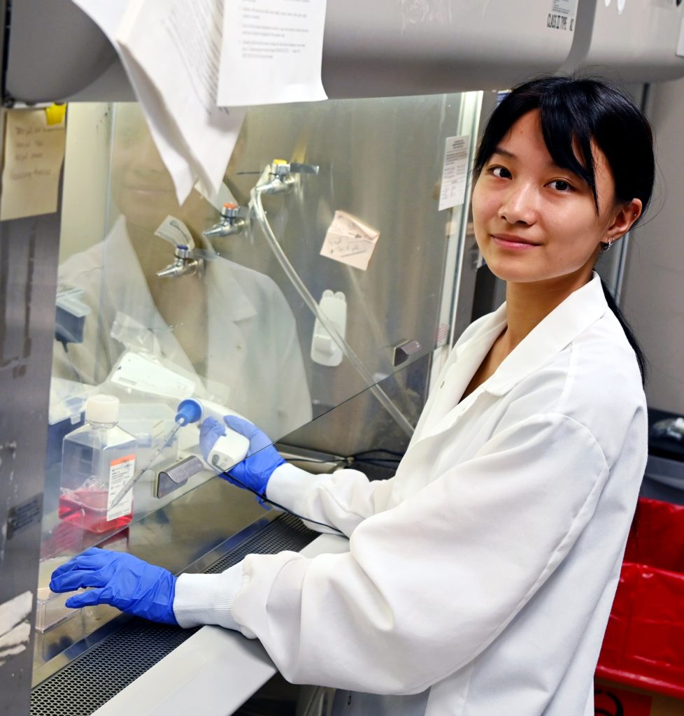 A high school student taking part in a summer scholars program learns about proper lab techniques.
