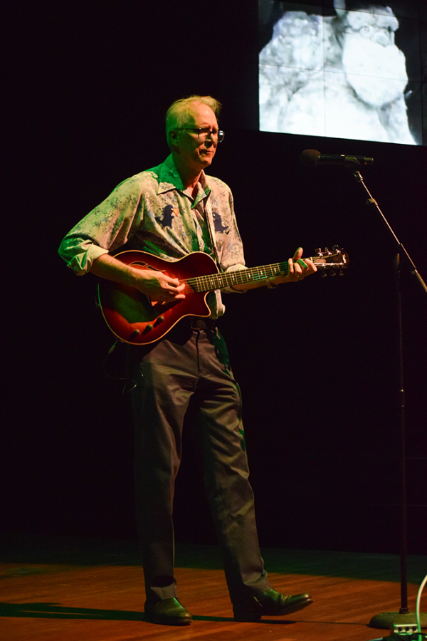 A man plays a guitar and sings on stage.