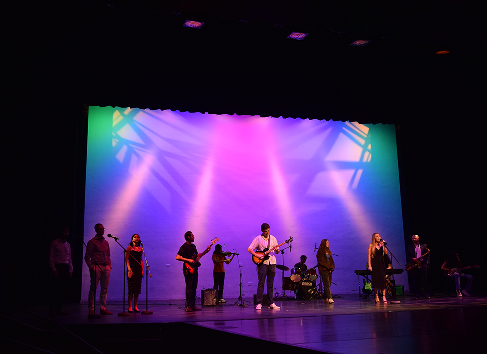 A band made up of men and women perform on stage.
