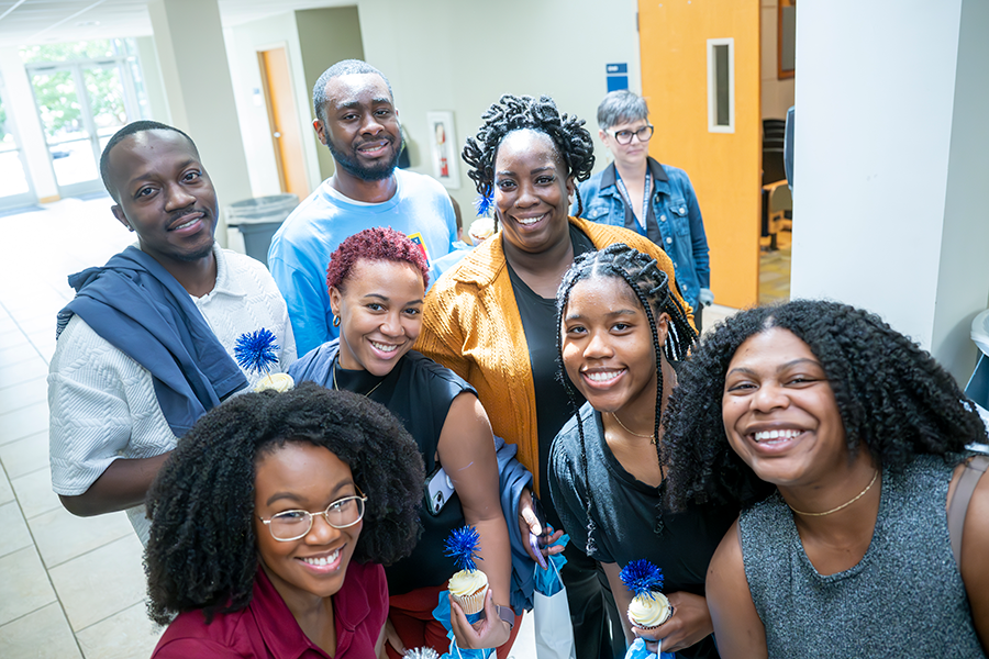 Seven college students, including five women and two men, take part in a celebration inside an auditorium.
