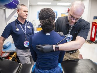 Two male doctors examining a female athlete