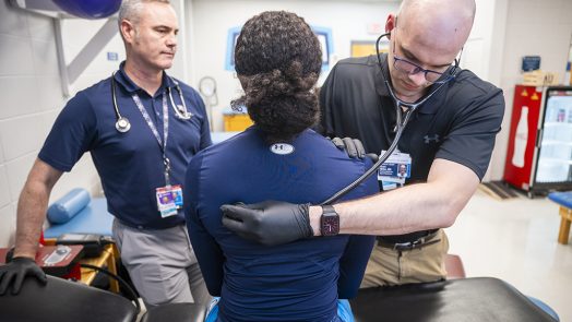 Two male doctors examining a female athlete