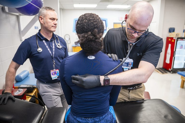 Two male doctors examining a female athlete