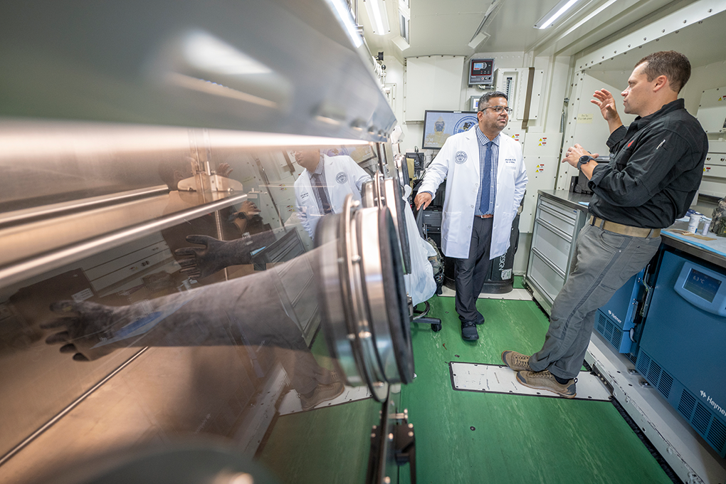 A doctor and a U.S. Air Force captain stand in a mobile laboratory truck and talk to each other.
