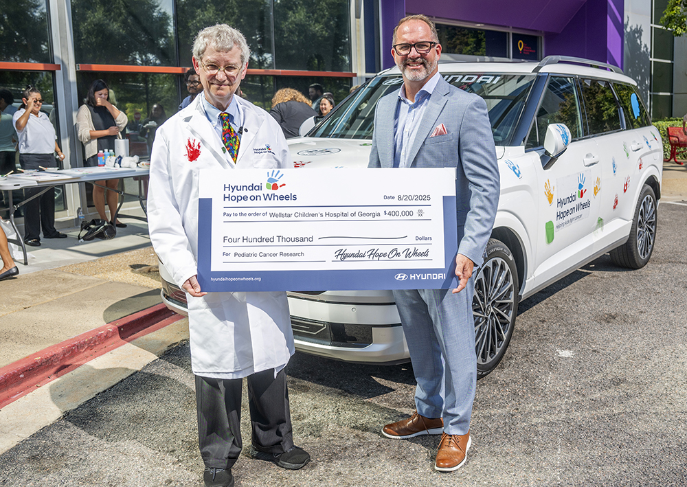 Two men hold oversized check