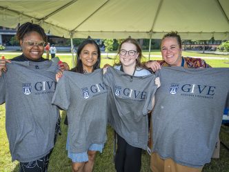 Smiling ladies holding IGIVE t-shirts.