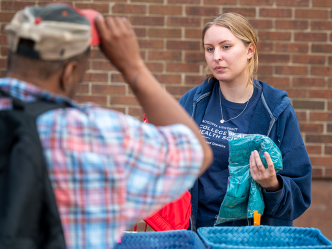 A female college student helps community members find new clothes during a mobile shower event.