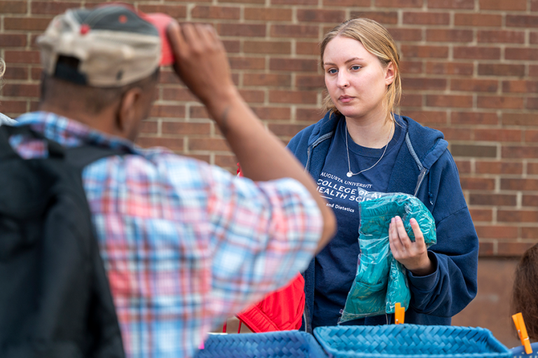 A female college student helps community members find new clothes during a mobile shower event.