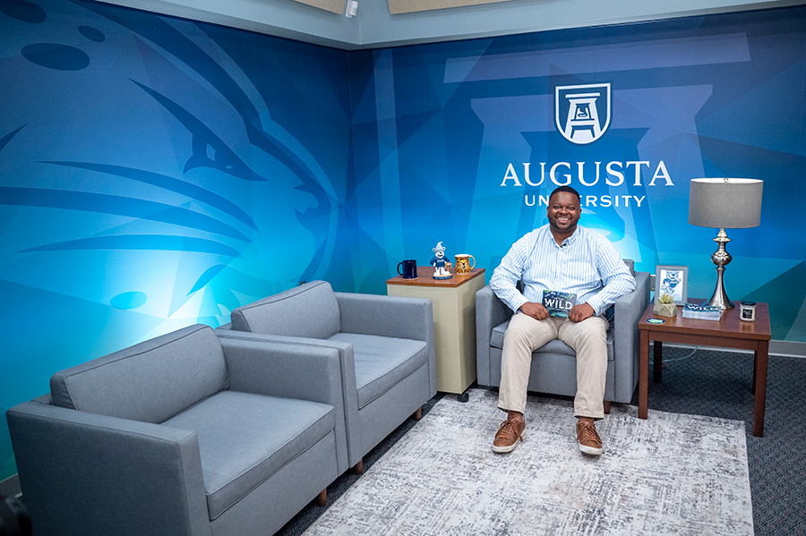 A man sits in an easy chair on the set of a podcast.